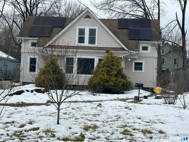 a view of a white house with snow on the road