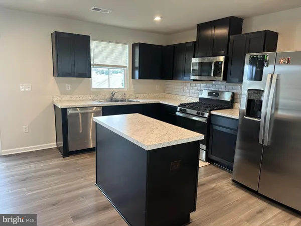 a kitchen with stainless steel appliances granite countertop a sink stove microwave and refrigerator