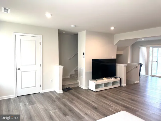 a view of an empty room with wooden floor and white walls