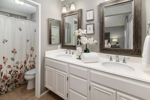 a bathroom with a double vanity sink mirror and toilet