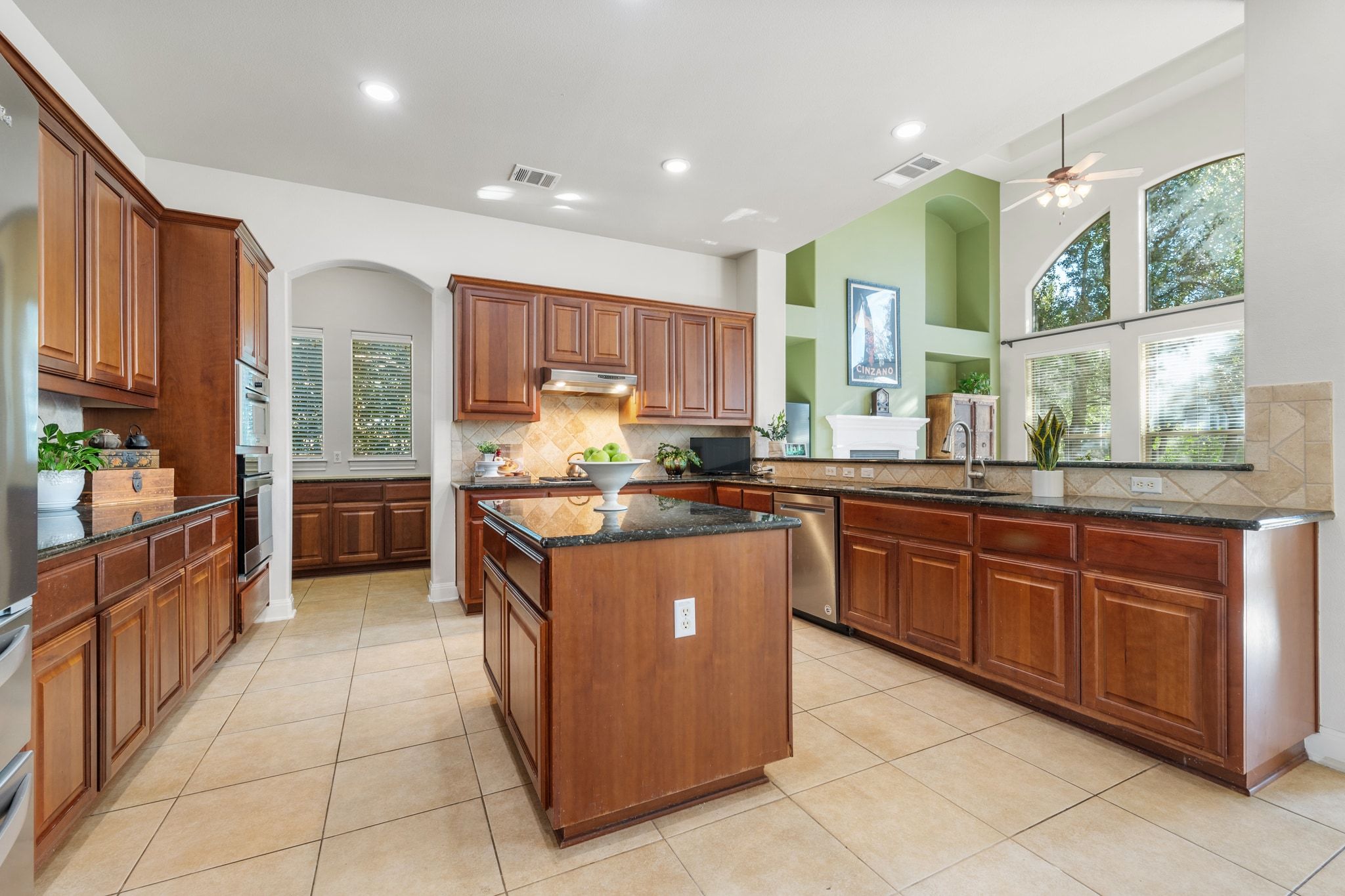 15201 Bat Hawk Circle Austin, TX 78738 - Photo 10 of 33 a kitchen with stainless steel appliances granite countertop wooden cabinets a sink a stove a chimney and a refrigerator