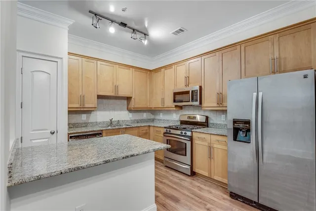 a kitchen with granite countertop a refrigerator a sink a stove a microwave and island