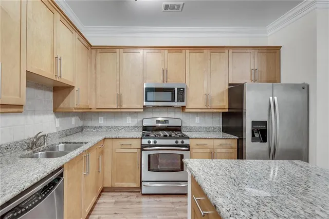 a kitchen with stainless steel appliances granite countertop a stove a refrigerator and a sink