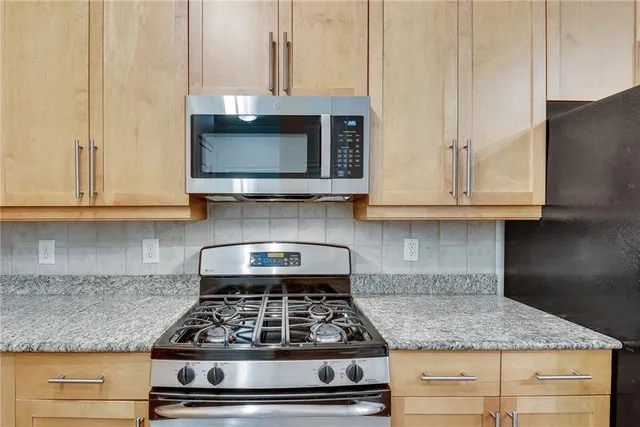 a kitchen with granite countertop white cabinets stainless steel appliances and a counter space