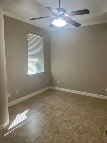an empty room with a chandelier fan and windows