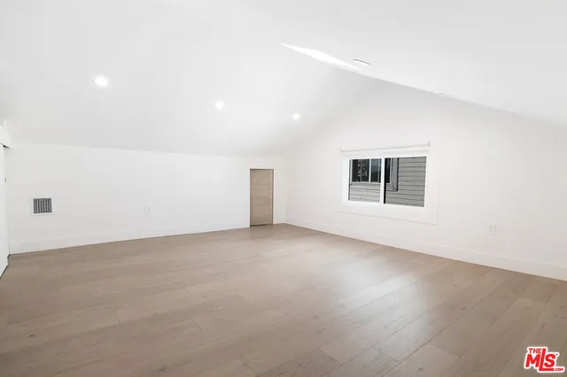 an empty room with wooden floor and natural light
