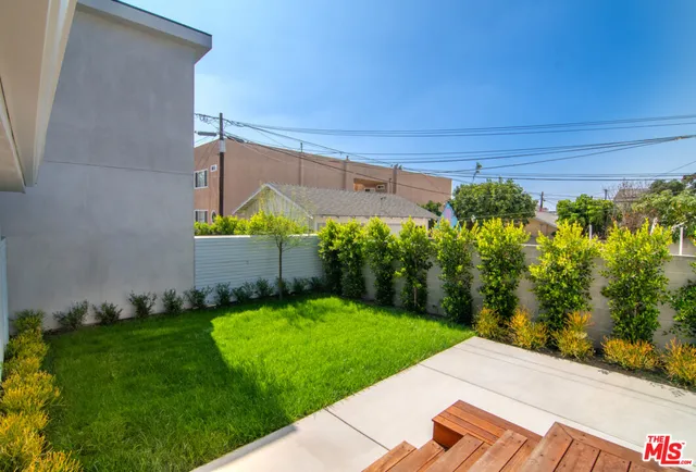 a backyard of a house with plants and large tree