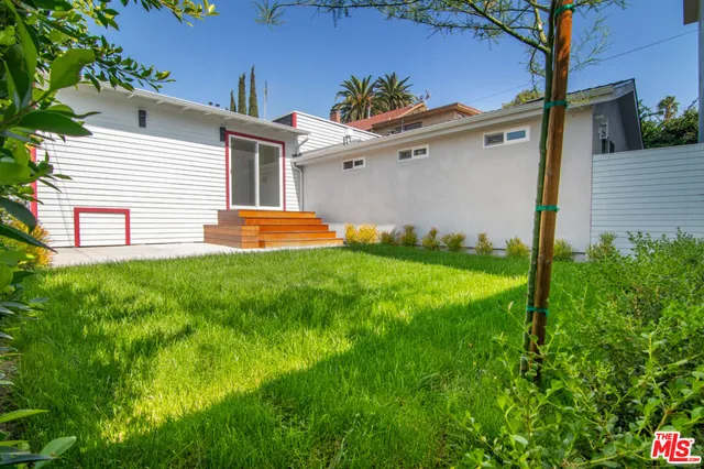 a backyard of a house with plants and large tree
