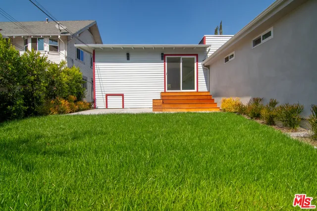 a backyard of a house with barbeque oven and potted plants