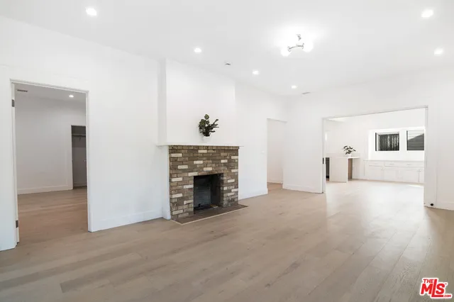 a view of empty room with wooden floor and fireplace