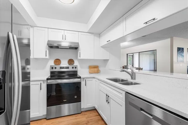 a kitchen with stainless steel appliances a refrigerator a stove and white cabinets