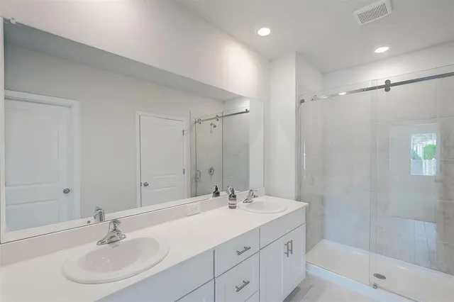 a bathroom with a sink double vanity granite tub and a mirror