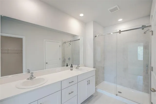 a bathroom with a shower sink double mirror and vanity