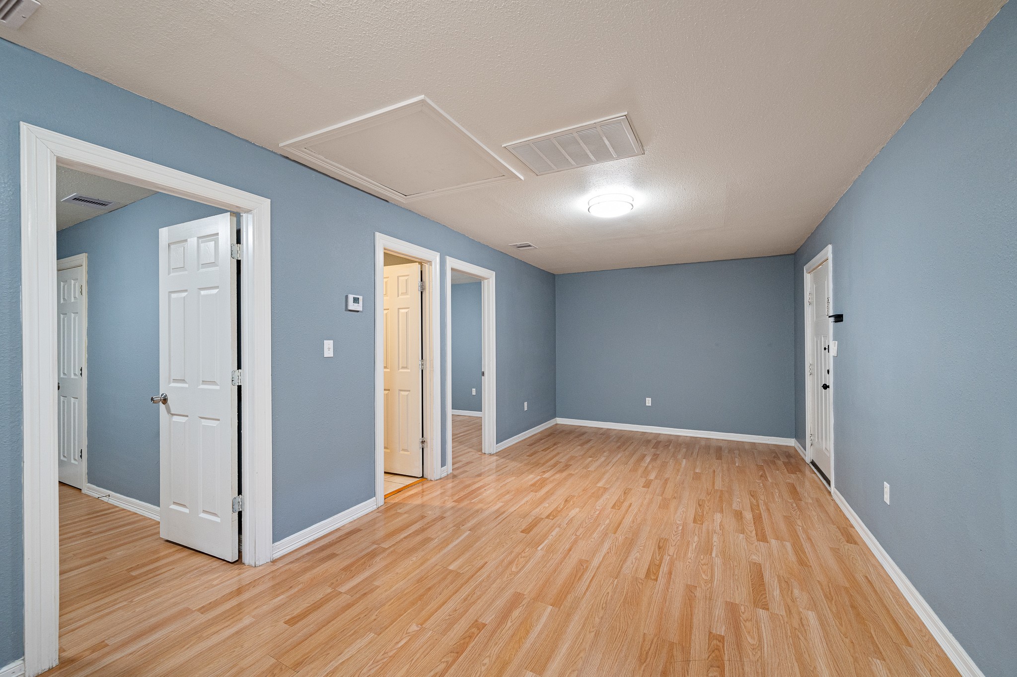 7815 Harding Street, Unit B Houston, TX 77012 - Photo 9 of 21 From the kitchen, enjoy a seamless transition into a spacious living room, featuring warm floors and soft blue walls, perfect for relaxation and entertaining.