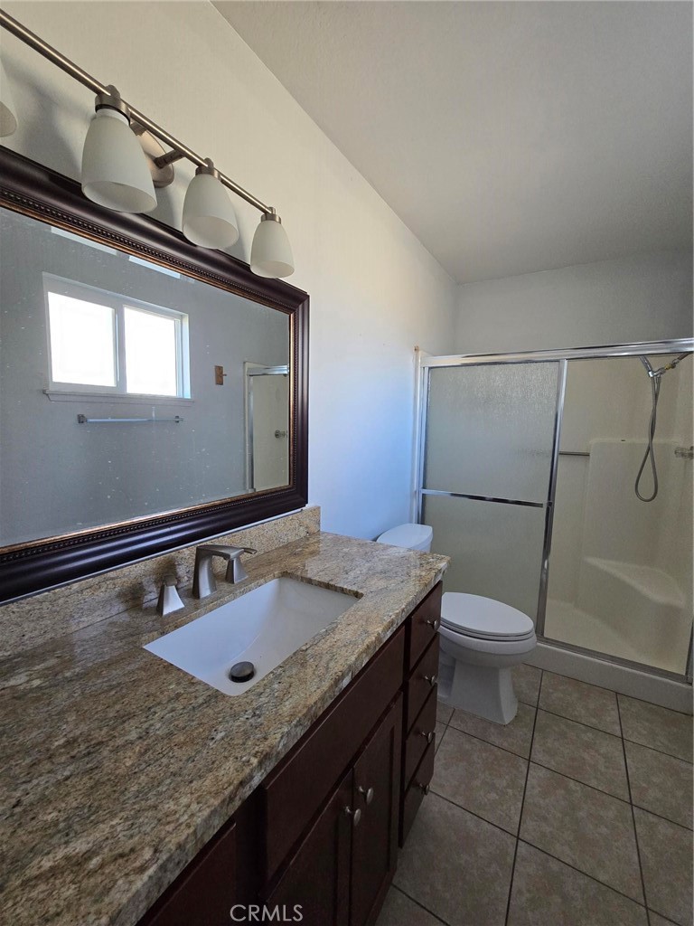 11876 Puye Road Apple Valley, CA 92308 - Photo 8 of 9 a bathroom with a granite countertop sink a toilet a mirror and shower