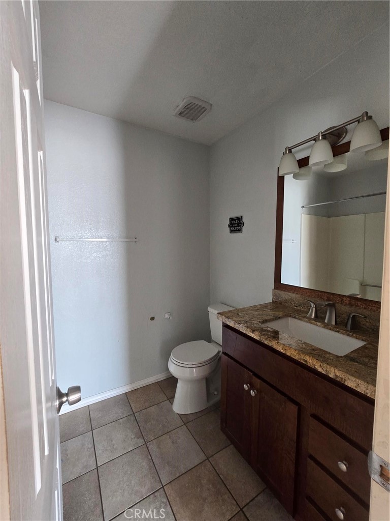 11876 Puye Road Apple Valley, CA 92308 - Photo 9 of 9 a bathroom with a granite countertop sink a toilet and a mirror