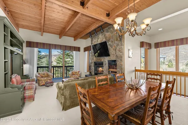 a view of a dining room with furniture a chandelier and large windows
