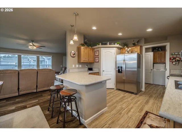 a kitchen with stainless steel appliances kitchen island granite countertop a refrigerator a sink a stove and a microwave with wooden floor