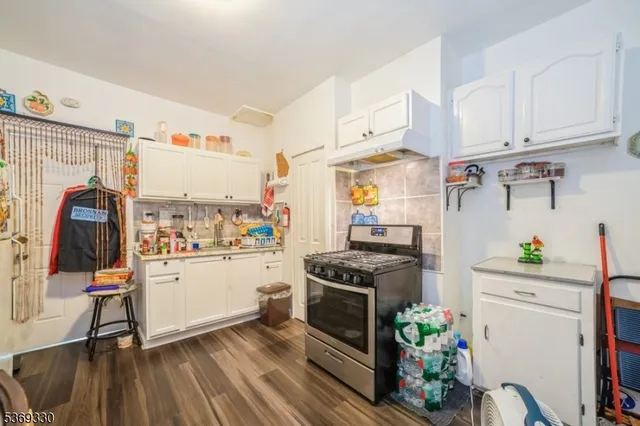 a kitchen with stainless steel appliances a stove a chimney a refrigerator and cabinets