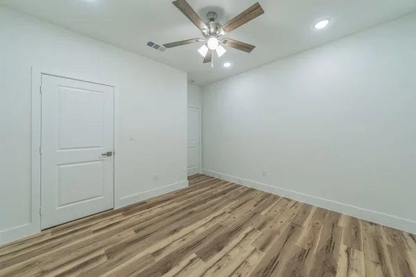 wooden floor in an empty room with a chandelier fan
