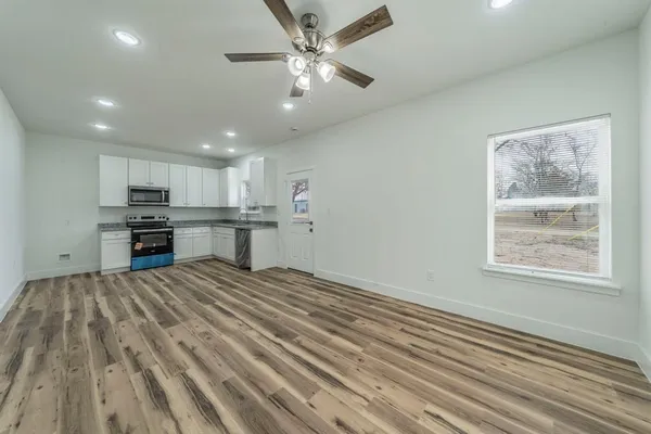 a view of kitchen and empty room with wooden floor