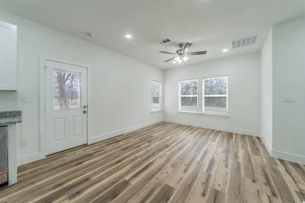a view of an empty room with a window and wooden floor