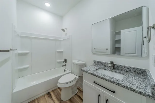a bathroom with a granite countertop sink a toilet and bathtub