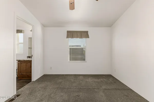 an empty room with a chandelier fan and windows