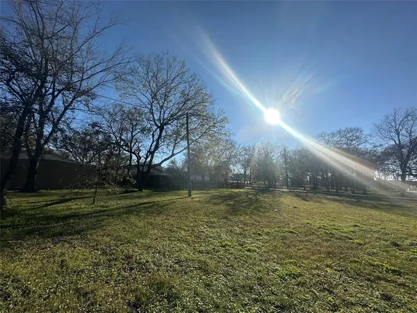 a yard with a house and trees in the background
