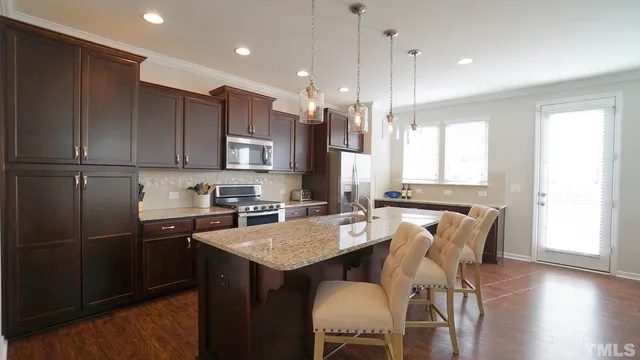 a kitchen with kitchen island granite countertop a sink a counter space appliances and cabinets