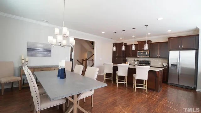 a kitchen with stainless steel appliances kitchen island granite countertop a dining table chairs and a refrigerator