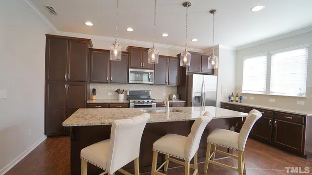a kitchen with kitchen island granite countertop a table chairs sink and microwave