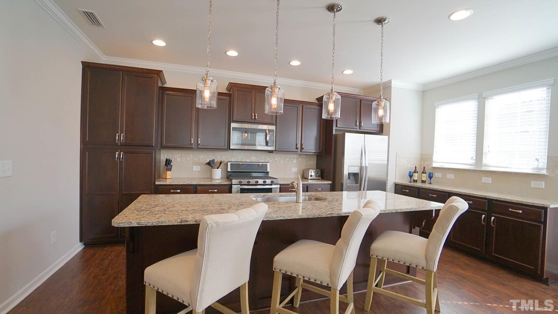 540 Metro Station Apex, NC 27502 - Photo 26 of 45 a kitchen with kitchen island granite countertop a table chairs sink and microwave
