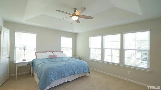 a bedroom with a large bed and a chandelier fan