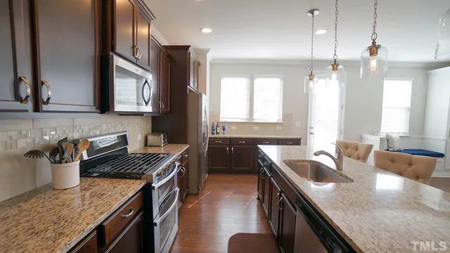 a kitchen with stainless steel appliances granite countertop a sink a stove and a wooden floors