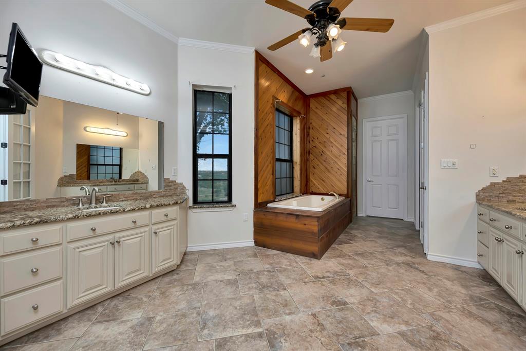 5520 White Settlement Road Weatherford, TX 76087 - Photo 27 of 39 Bathroom featuring ornamental molding, ceiling fan, vanity, stone finish flooring, and a bath