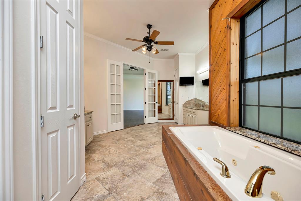5520 White Settlement Road Weatherford, TX 76087 - Photo 29 of 39 Full bath with french doors, a ceiling fan, crown molding, vanity, and a jetted tub