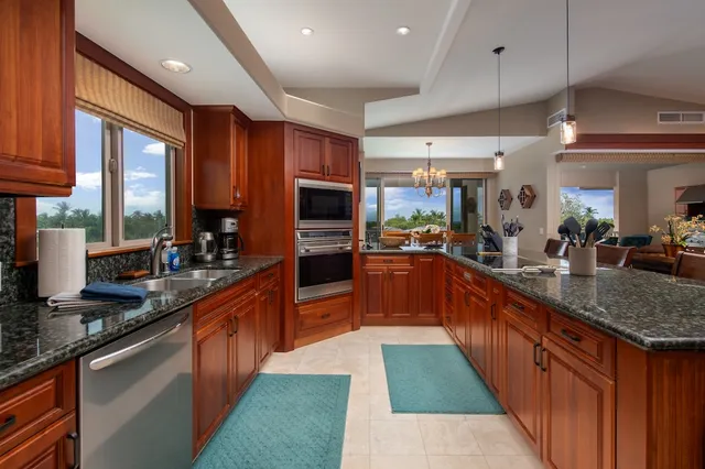 a large kitchen with stainless steel appliances kitchen island granite countertop a sink counter space cabinets and a large window