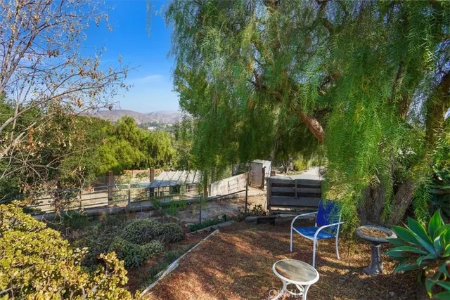 a backyard of a house with table and chairs potted plants and large trees