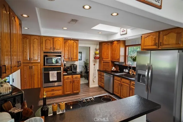 a kitchen with stainless steel appliances granite countertop a refrigerator a stove top oven a sink and dishwasher