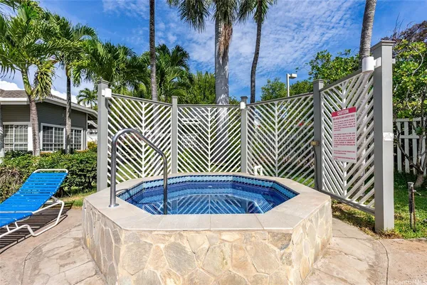 a view of a swimming pool with a lawn chairs under palm trees