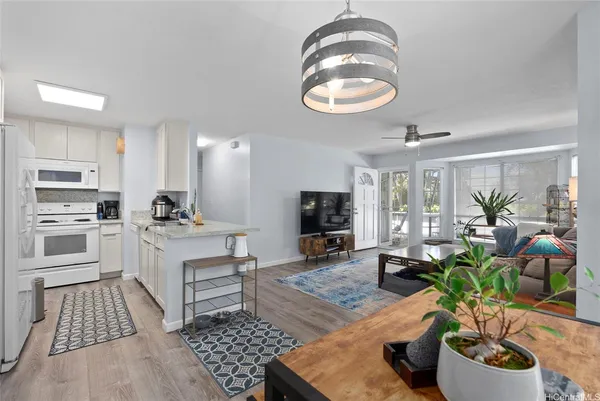 a kitchen with sink stove and white cabinets with wooden floor