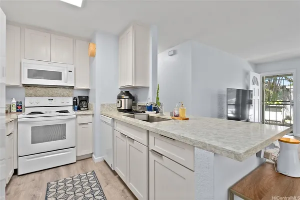 a kitchen with granite countertop white cabinets and white appliances