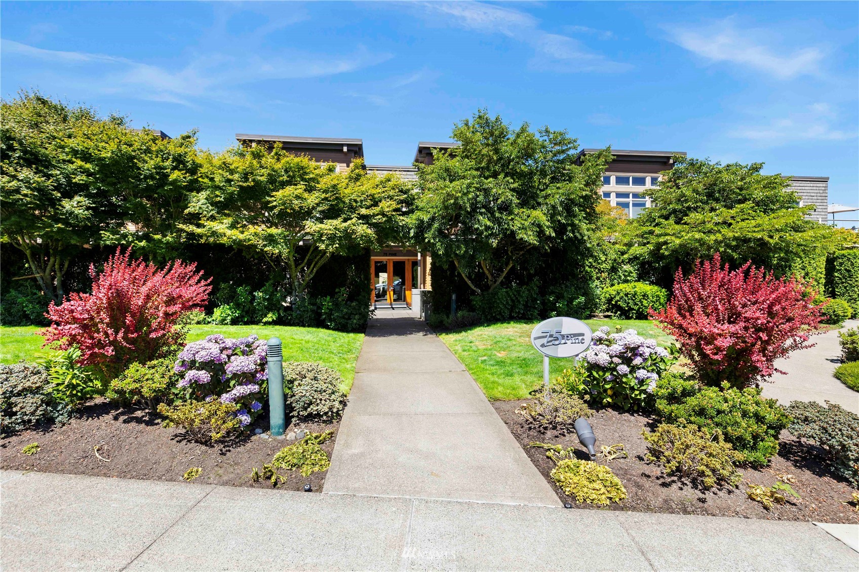 75 Pine Street, Unit 205 Edmonds, WA 98020 - Photo 2 of 33 a view of a pathway with flower plants and large trees
