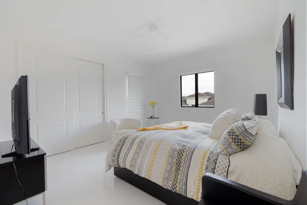 a bedroom with a bed and a flat tv screen next to a window