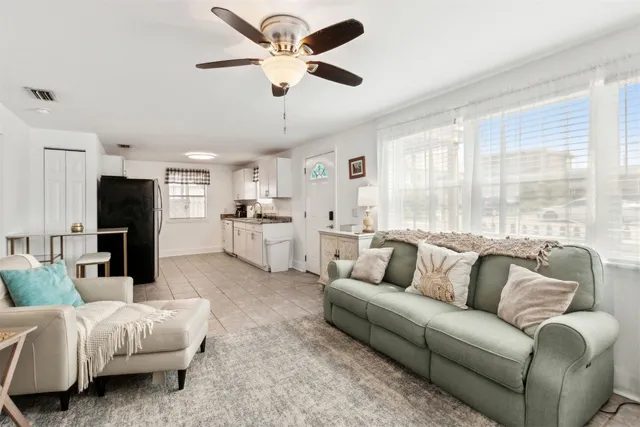 a living room with furniture and a large window with kitchen view