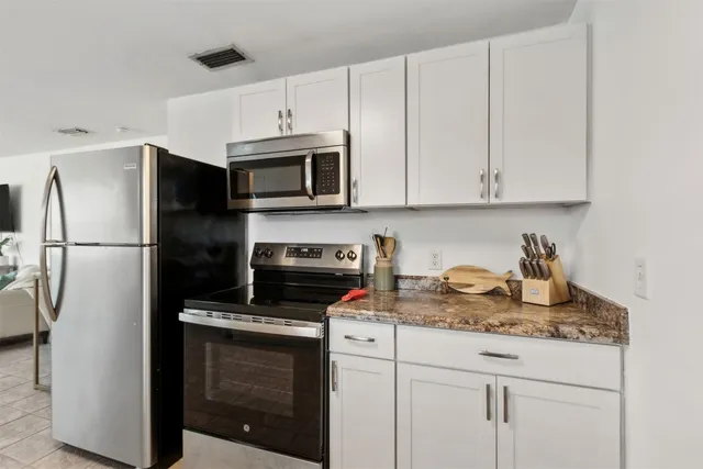 a kitchen with granite countertop white cabinets and stainless steel appliances