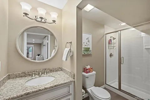 a bathroom with a granite countertop toilet a sink and a mirror