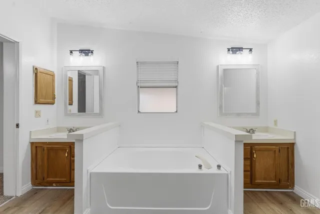 a bathroom with a tub a sink and mirror