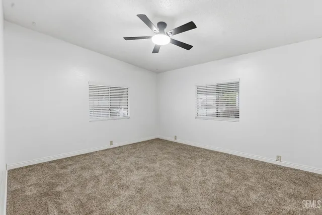 an empty room with ceiling fan and windows
